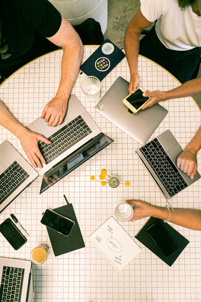 Home Top view of a team collaborating with laptops, phones, and notes in a modern office.